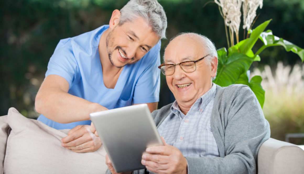Happy Caretaker And Senior Man Using Tablet PC
