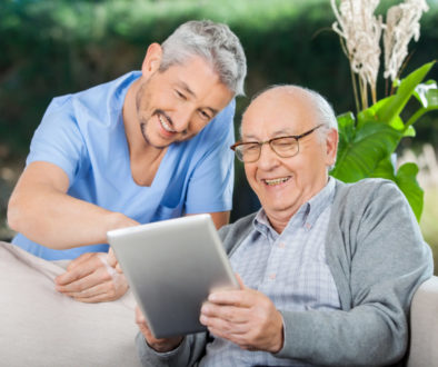 Happy Caretaker And Senior Man Using Tablet PC